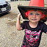 Everleigh joined the competition — help win amazing prizes! child, toddler, portrait, smiling, outdoor, driveway, traffic_cone, costume, hat, red_hat, black_shirt, racing_shirt, pink_clothing, toy_car, cars, tricycle, shoes, blue_eyes, standing, playful
