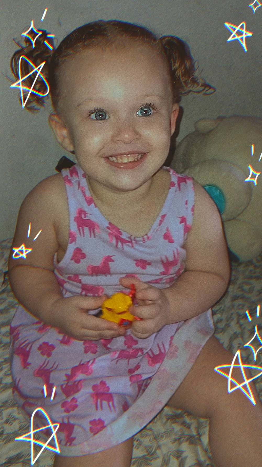 Kiowa joined the competition — help win amazing prizes! bed, blanket, casual, child, cute, dress, face, happy, indoor, pattern, person, pigtails, playful, plush_toy, sitting, smiling, star_doodles, toddler, toy, young_child