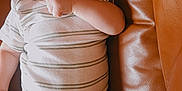 Declan is registered to the contest to win money with this photo: baby, infant, smiling, face, person, striped_shirt, white_pants, couch, leather, cozy, indoors, cute, happy, child, young, lying_down, hand, expression, comfort, soft_lighting
