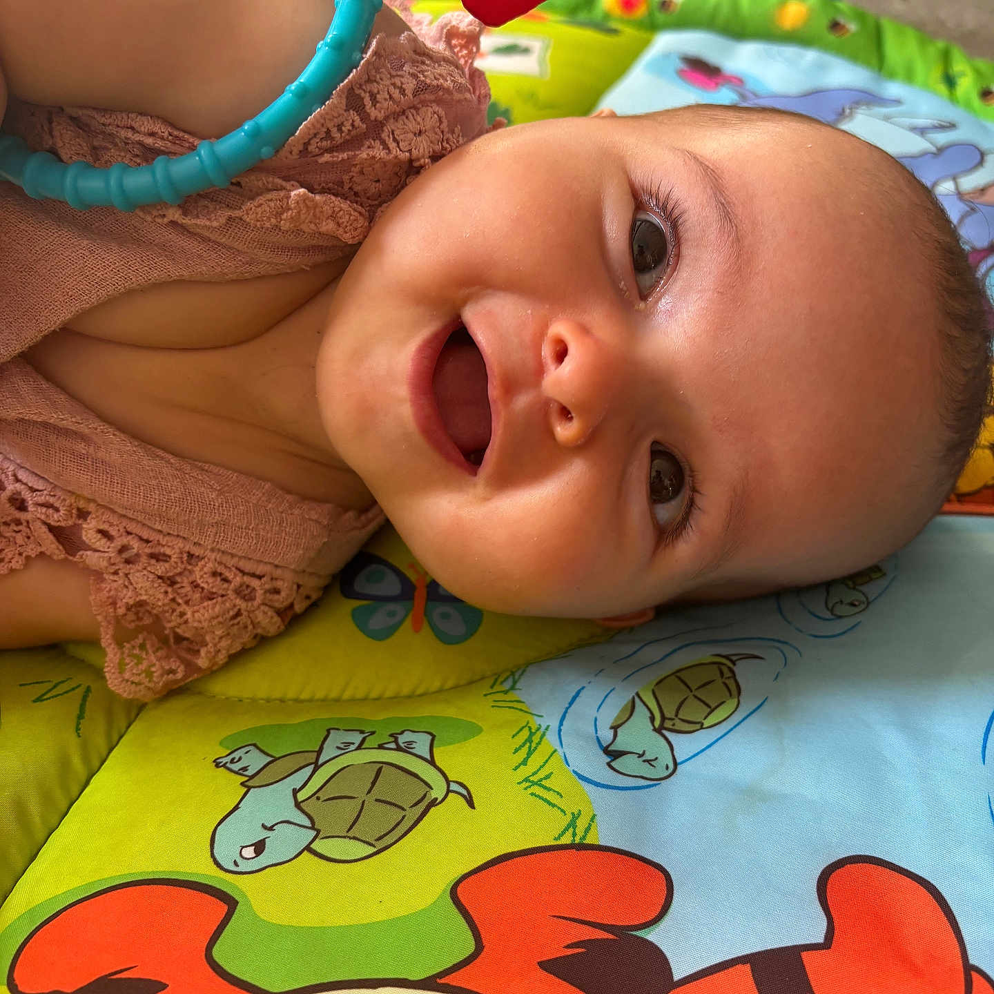 Nëlya participe au concours pour gagner de l'argent avec cette photo : baby, butterfly, child, close_up, clothing, colorful, cute, eyes, face, happy, head, indoors, infant, lying_down, mouth, play_mat, skin, smiling, toy, turtle