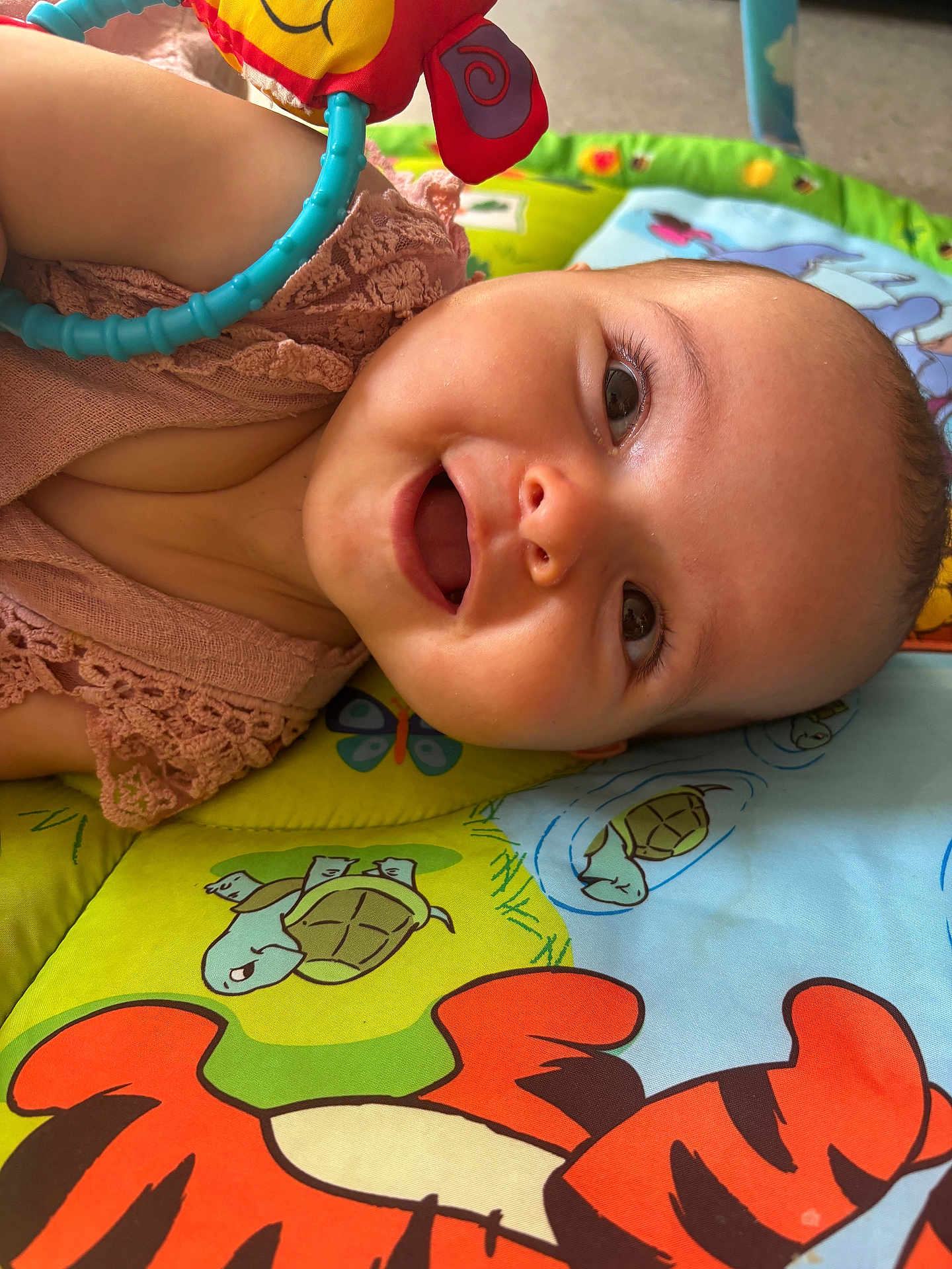 Nëlya participe au concours pour gagner de l'argent avec cette photo : baby, butterfly, child, close_up, clothing, colorful, cute, eyes, face, happy, head, indoors, infant, lying_down, mouth, play_mat, skin, smiling, toy, turtle