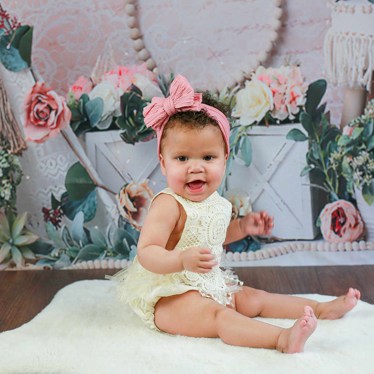 Marliyah-Raine is registered to the contest to win money with this photo: baby, child, cute, decor, dress, floral_backdrop, flower, girl, greenery, happy, headband, indoor, lace, pink_bow, portrait, pot_plants, sitting, smiling, white_rug, wooden_floor