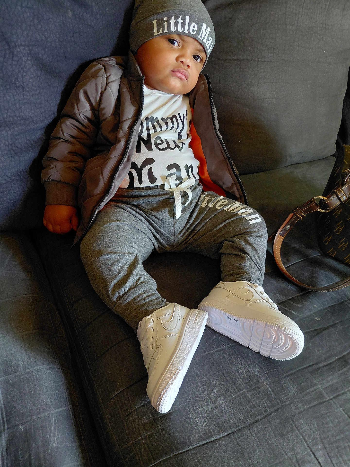 Brayden Cherry is registered to the contest to win money with this photo: child, kid, beanie, hat, jacket, white_sneakers, pants, couch, sofa, bag, fashion, indoor, portrait, clothing, casual, footwear, person, sitting, young, expression