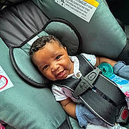 Christian joined the competition — help win amazing prizes! baby, car_seat, child, smiling, curly_hair, mittens, pacifier, seatbelt, infant, clothing, happy, portrait, safety, warning_label, closeup, cute, indoors, child_safety, seat, restraint
