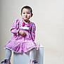 child, toddler, pink_dress, bow, white_tights, boots, purple_laces, sitting, white_cube, funny_face, studio, indoor, portrait, cute, expression, fashion, young_child, pouting, light_background, short_hair