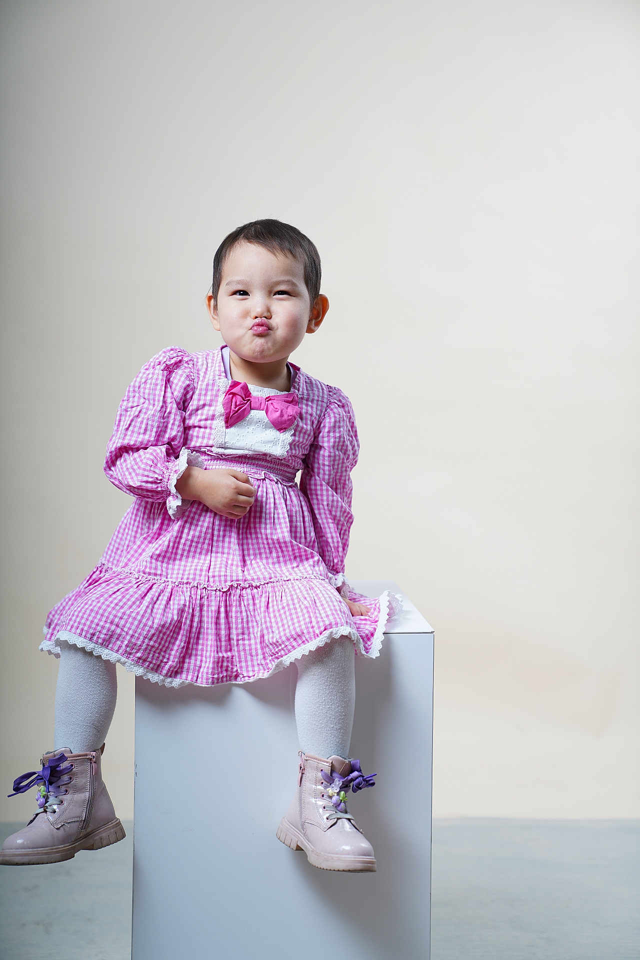 Tenuunjargalan a rejoint le concours — aidez-le/la à gagner de superbes lots ! child, toddler, pink_dress, bow, white_tights, boots, purple_laces, sitting, white_cube, funny_face, studio, indoor, portrait, cute, expression, fashion, young_child, pouting, light_background, short_hair