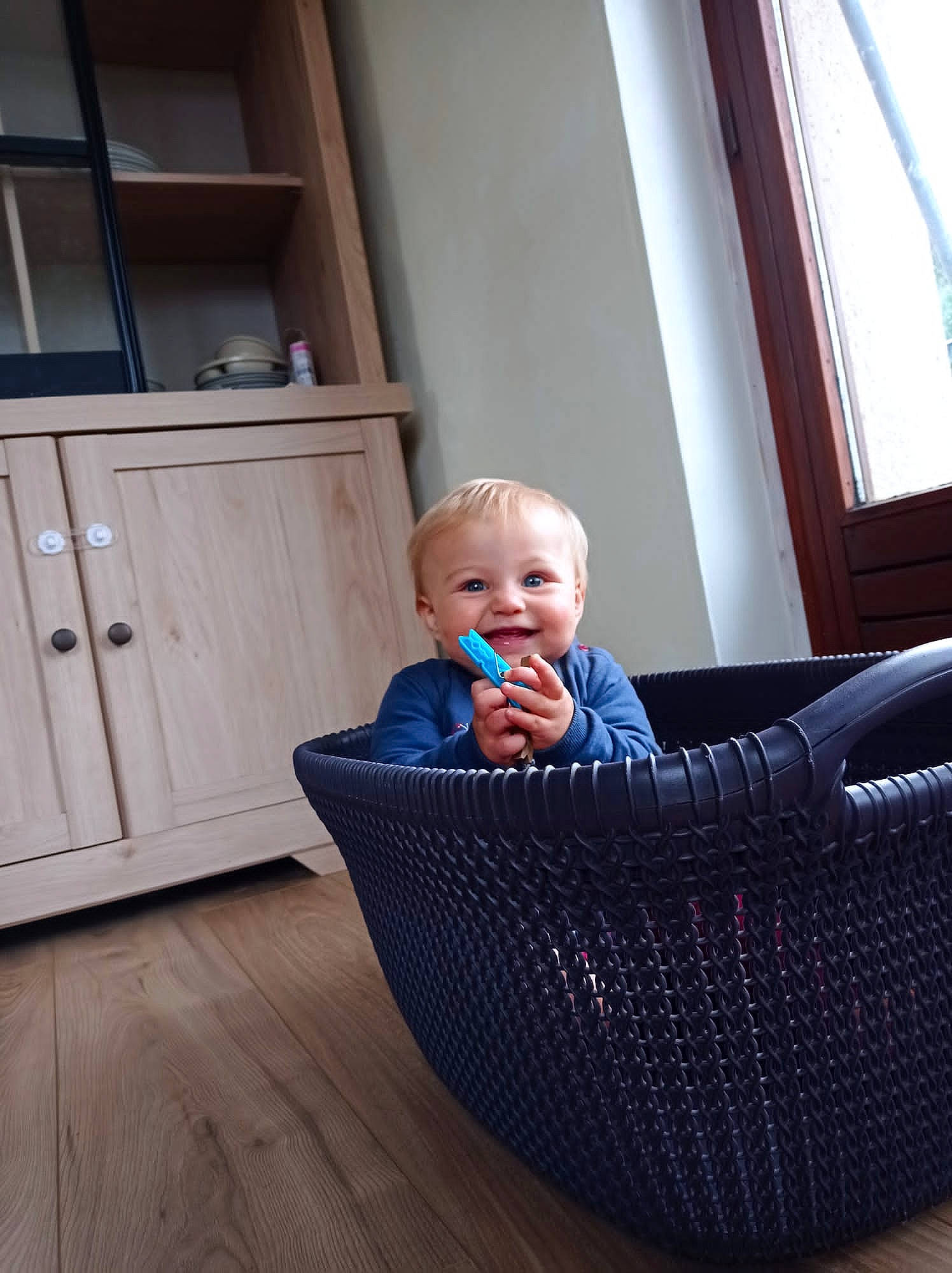 Louise participe au concours pour gagner de l'argent avec cette photo : baby, baby_safety, baby_toddler_clothing, cabinetry, cleanliness, comfort, electric_blue, floor, flooring, fun, hardwood, joy, leisure, person, room, sitting, toddler, varnish, window, wood