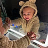 baby, child, infant, mirror, reflection, smiling, happy, teddy_bear_hood, fleece_outfit, hooded_jacket, bathroom, countertop, sink, toiletries, indoor, portrait, close_up, hand, parent, playful