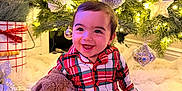 Jordan is registered to the contest to win money with this photo: baby, child, pajamas, plaid, stuffed_animal, bunny, toy, christmas_tree, ornaments, lights, holiday, festive, smiling, happy, indoor, blanket, cozy, decorations, face, cute