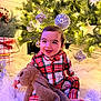 baby, child, pajamas, plaid, stuffed_animal, bunny, toy, christmas_tree, ornaments, lights, holiday, festive, smiling, happy, indoor, blanket, cozy, decorations, face, cute