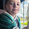 child, boy, portrait, smile, casual, window, indoor, clothing, hoodie, green_jacket, face, young, person, daylight, background, trees, outdoor_blur, expression, head, leisure