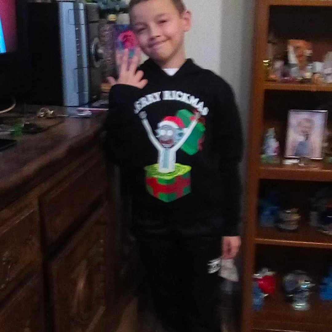 Loucas joined the competition — help win amazing prizes! black_clothing, boy, casual, child, fingers, floor, home, hoodie, indoors, knick_knacks, person, photograph, pose, room, shelf, smile, sneakers, tiles, wooden_furniture, young