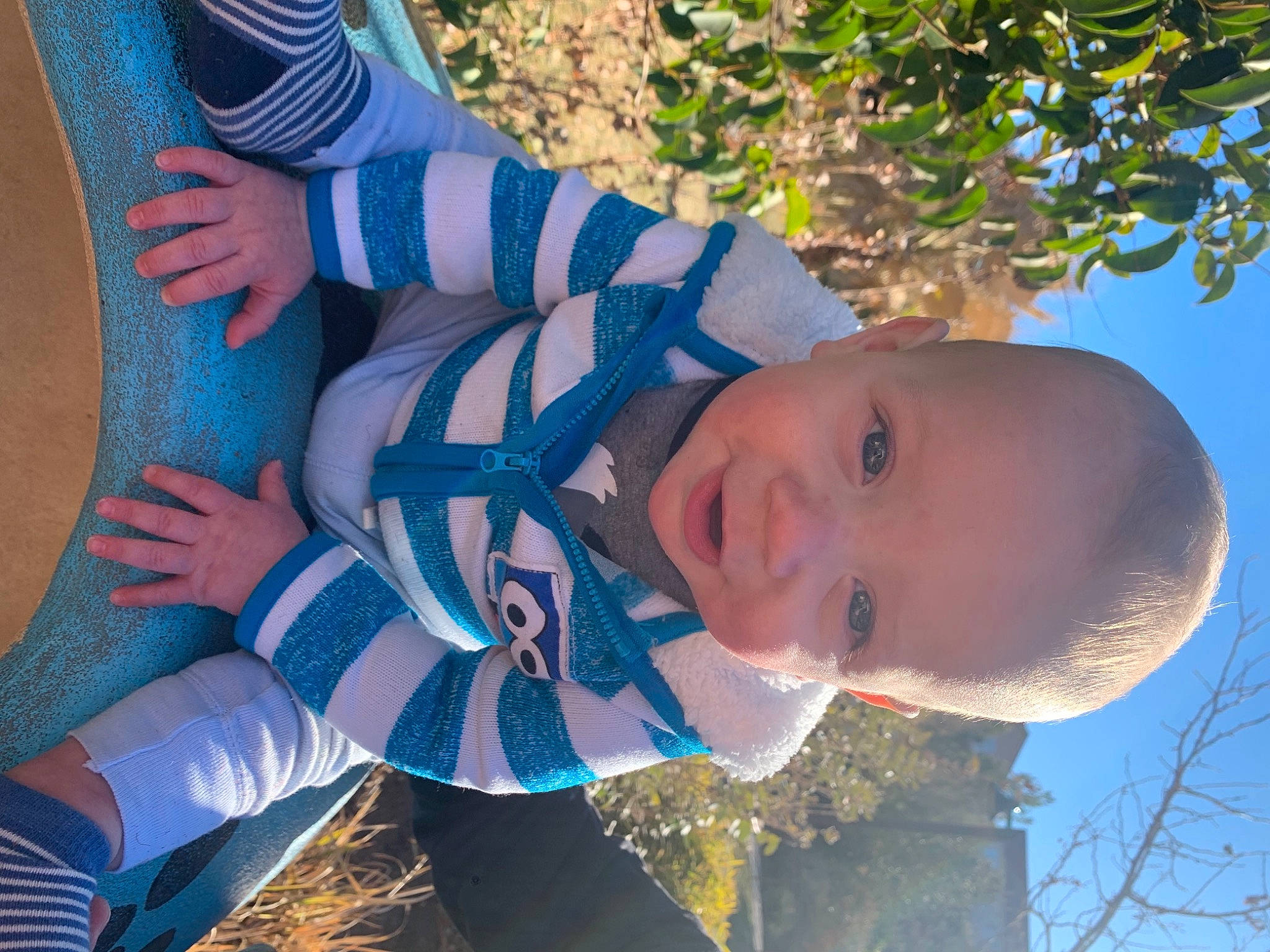 Tyden is registered to the contest to win money with this photo: arm, azure, baby, blue, electric_blue, face, fun, grass, happy, human_body, leisure, light, people_in_nature, person, photograph, plant, skin, sky, thigh, toddler