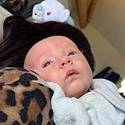 Alessio a rejoint le concours — aidez-le/la à gagner de superbes lots ! baby, infant, face, blue_eyes, blanket, leopard_print, stuffed_animal, white_clothing, indoor, portrait, child, soft_toy, cozy, resting, cute, young_child, head, expression, person, home_interior