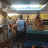 dog, boat, cockpit, cabin, indoors, people, driver, passenger, bench, seating, controls, steering, window, outdoors, watercraft, travel, adventure, daylight, golden_hour, pet
