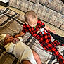 baby, child, infant, couch, blanket, floor, pajamas, onesie, hat, pacifier, carpet, indoor, sibling, cute, relaxing, laying_down, plaid, pattern, person, home