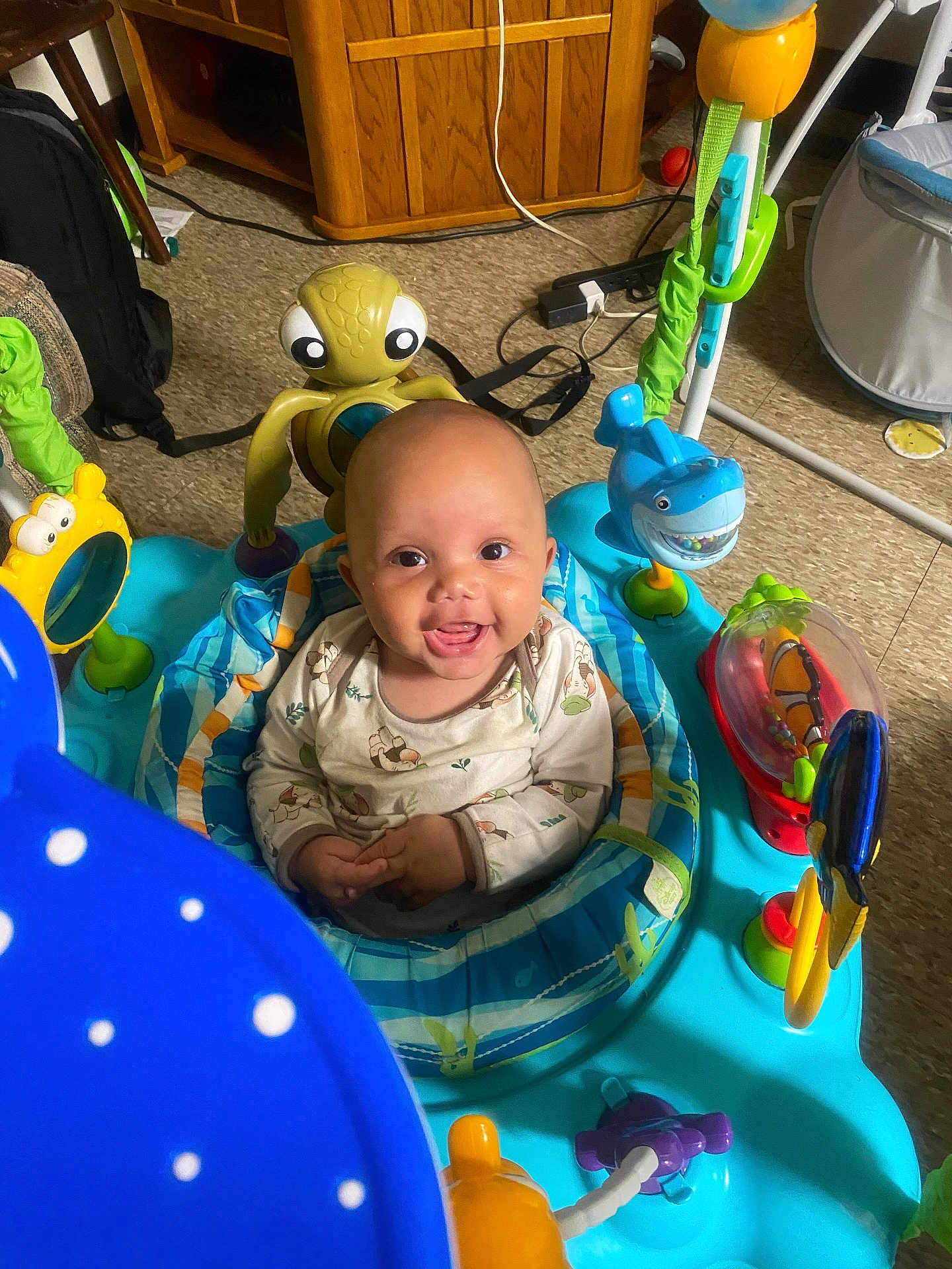 Theodore is registered to the contest to win money with this photo: baby, smiling, activity_center, toys, indoor, child, happy, seat, play, colorful, infant, floor, clothing, person, cute, looking_at_camera, bright_eyes, fun, early_childhood, playful