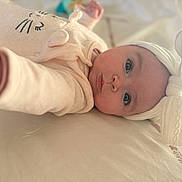 Cassie a rejoint le concours — aidez-le/la à gagner de superbes lots ! baby, infant, headband, white_bow, blue_eyes, cozy_clothing, soft_texture, cute, cute_face, lying_down, reaching_hand, indoors, portrait, child, adorable, soft_lighting, expression, close_up, baby_outfit, comfortable