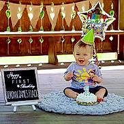 Jordan joined the competition — help win amazing prizes! baby, birthday, cake, party_hat, balloon, signboard, wooden_floor, smiling, celebration, child, plush_rug, number_candle, outdoor, decorations, happy, toddler, clothing, photography, first_birthday, portrait