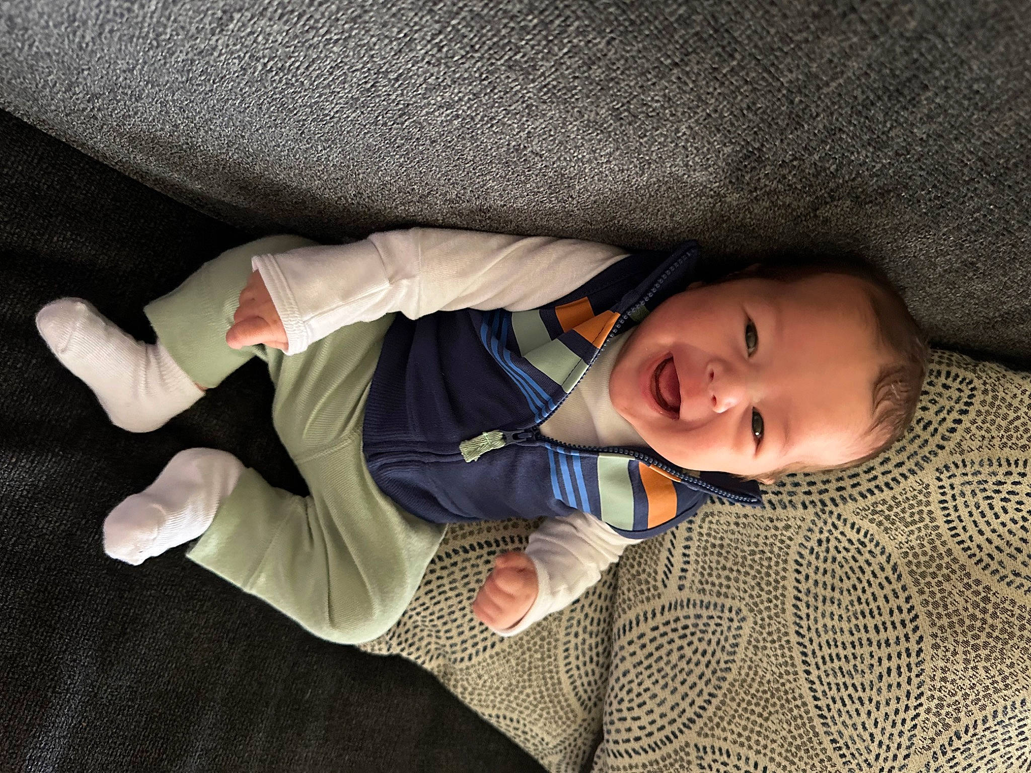 Luka is registered to the contest to win money with this photo: baby, baby_toddler_clothing, cheek, child, comfort, finger, flooring, human_leg, linens, nap, nose, pattern, person, sitting, skin, sleeve, smile, sock, thumb, toddler