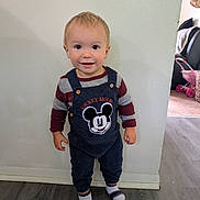 Waylon joined the competition — help win amazing prizes! toddler, child, smile, indoor, mickey_mouse, overalls, socks, striped, flooring, wall, person, standing, happy, cute, clothing, young_child, home, face, casual, portrait