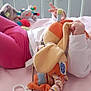 baby, bed, child, clothing, colorful, cozy, crib, cute, face, foot, hand, indoor, infant, lying_down, person, pink_bed, playful, soft_toy, stuffed_toy, toys