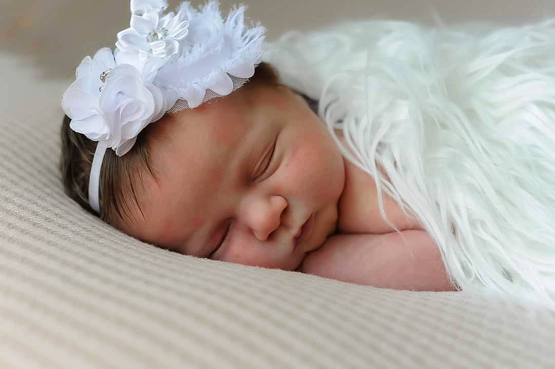 Charley is registered to the contest to win money with this photo: baby, baby_sleeping, baby_toddler_clothing, child, comfort, eyebrow, eyelash, facial_expression, finger, grass, hair_accessory, happy, headband, headgear, headpiece, iris, linens, mammal, person, skin