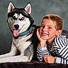 boy, child, husky, dog, pet, portrait, smiling, grinning, blue_eyes, heterochromia, striped_shirt, pajamas, animal, companion, indoor, studio, seated, lying_down, fur, friendship