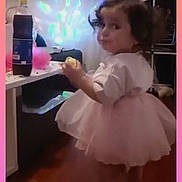 Maylesse a rejoint le concours — aidez-le/la à gagner de superbes lots ! toddler, child, pink_tutu, barefoot, indoor, wooden_floor, snack, curious, standing, sideways_glance, cozy_room, colorful_lights, household_items, curtains, table, bottle, casual, candid, portrait, young_child