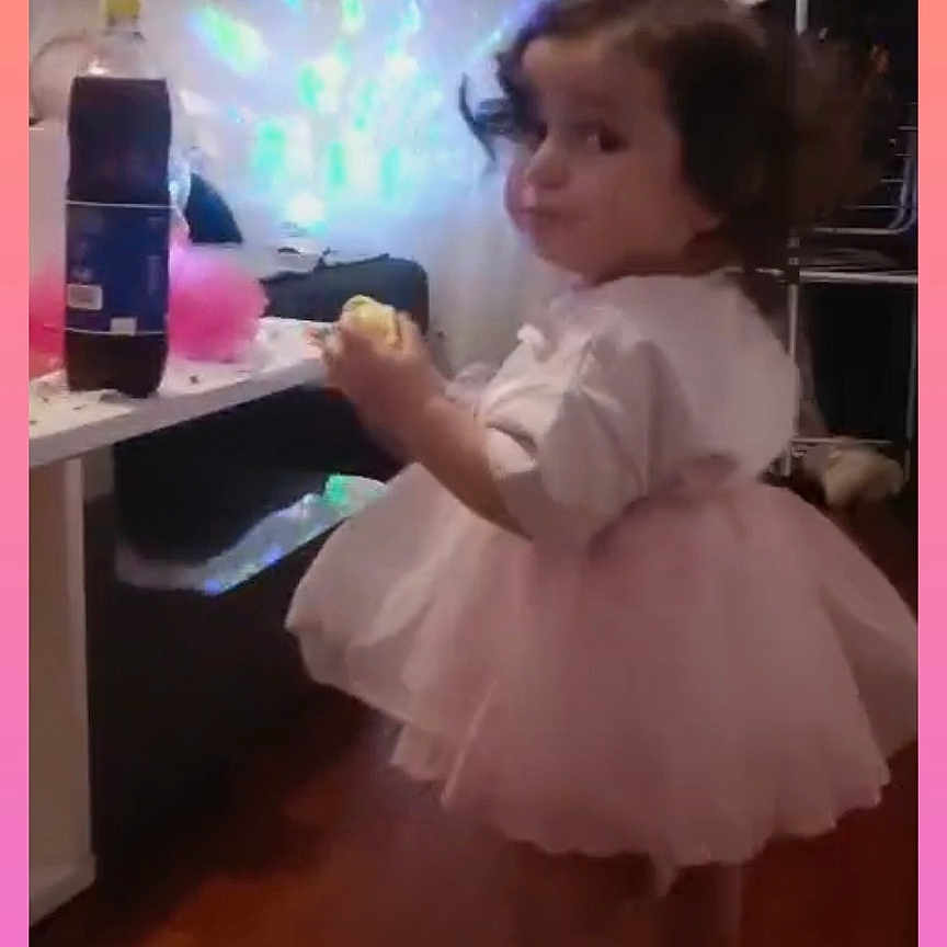 Maylesse a rejoint le concours — aidez-le/la à gagner de superbes lots ! barefoot, bottle, candid, casual, child, colorful_lights, cozy_room, curious, curtains, household_items, indoor, pink_tutu, portrait, sideways_glance, snack, standing, table, toddler, wooden_floor, young_child