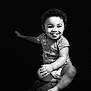 Aiden is registered to the contest to win money with this photo: arm, baby, barefoot, black_and_white, child, clothing, curly_hair, cute, dark_background, diaper, happy, infant, leg, playful, portrait, sitting, smiling, studio, tongue_out, watch