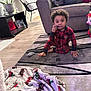 Aiden is registered to the contest to win money with this photo: blanket, chair, child, christmas, couch, decor, floor, holiday, home, indoor, living_room, pajamas, person, pillow, plaid, plant, rug, toddler, toy, wood_floor