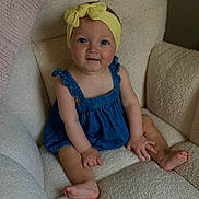 Kalani is registered to the contest to win money with this photo: baby, child, blue_eyes, yellow_headband, denim_romper, sitting, cozy_chair, textured_fabric, indoors, cute, smiling, barefoot, small_hands, portrait, infant, comfortable, soft_lighting, happy, young, headwear