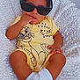 baby, child, sunglasses, yellow_onesie, white_socks, blanket, infant, cute, indoor, portrait, smiling, baby_clothes, soft_texture, plush, relaxed, fashion, toddler, person, cozy, toy