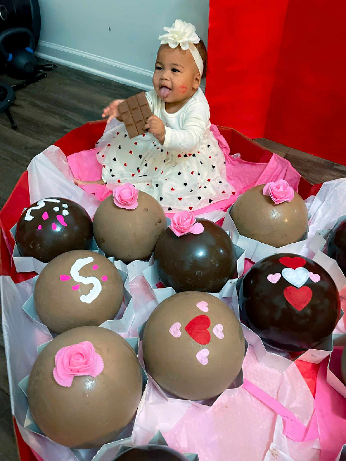 Kayzlee joined the competition — help win amazing prizes! baby, child, girl, dress, headband, flower, chocolate, giant_chocolates, gift_box, pink, heart_pattern, tongue_out, kiss_mark, floor, wooden_floor, indoor, celebration, cute, smiling, sitting