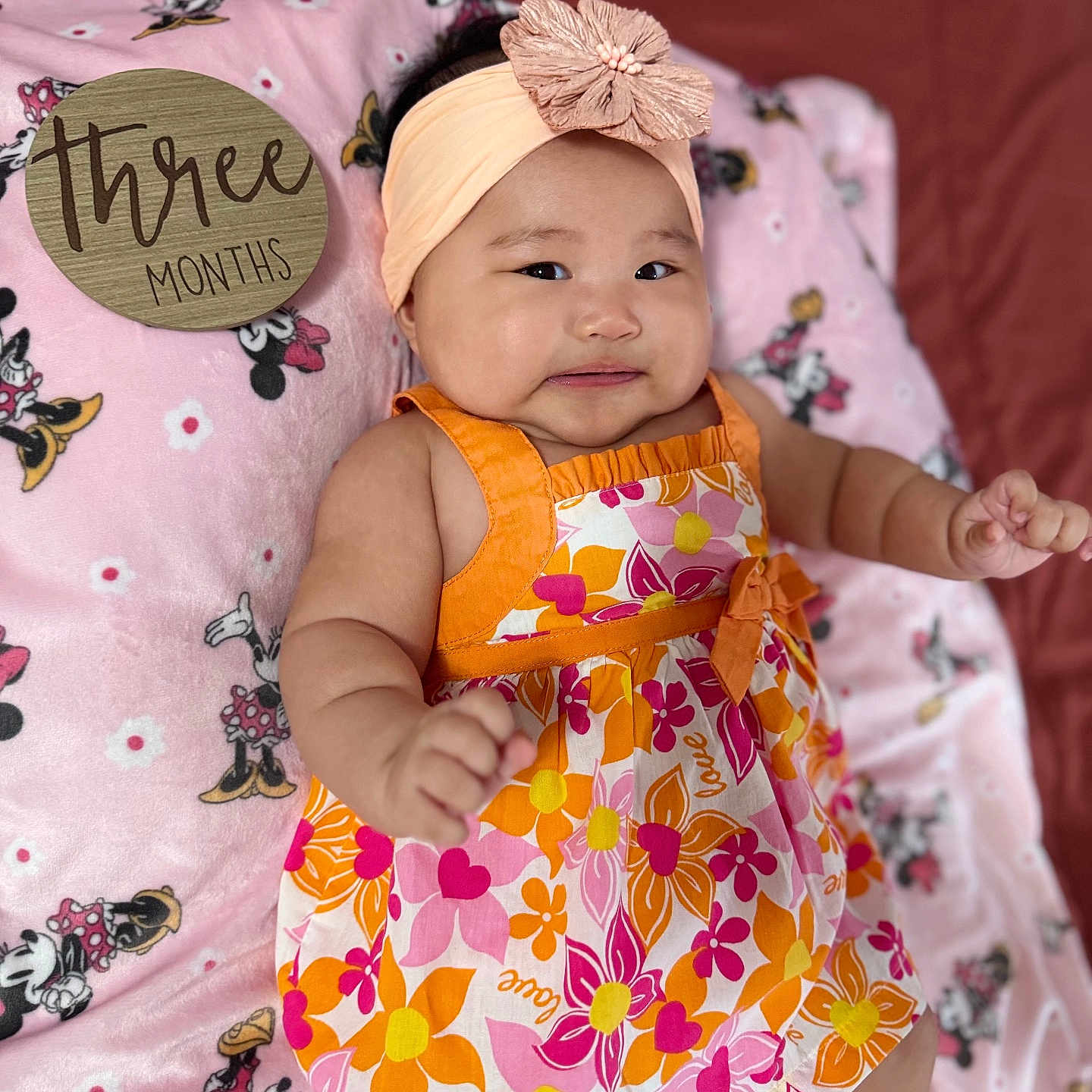 Yennica joined the competition — help win amazing prizes! baby, blanket, child, cute, dress, floral_pattern, girl, headband, indoors, infant, lying_down, milestone, minnie_mouse, orange, pink, portrait, smiling, soft_texture, three_months, wooden_sign
