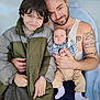 Maverick is registered to the contest to win money with this photo: child, baby, man, family, smile, tattoo, jacket, clothing, holding, embrace, indoor, portrait, person, sitting, blue, beige, checkered, happy, cute, casual