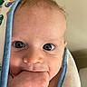 Weston is registered to the contest to win money with this photo: baby, closeup, face, hand, towel, blue_trim, skin, eyes, infant, cute, child, portrait, expression, curious, indoor, human, fingers, mouth, newborn, soft_lighting
