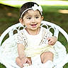 baby, child, cute, grass, greenery, happy, headband, infant, lace_dress, nature, outdoor, playful, portrait, sitting, smiling, soft_blanket, sunlight, white_bow, white_clothing, wicker_chair