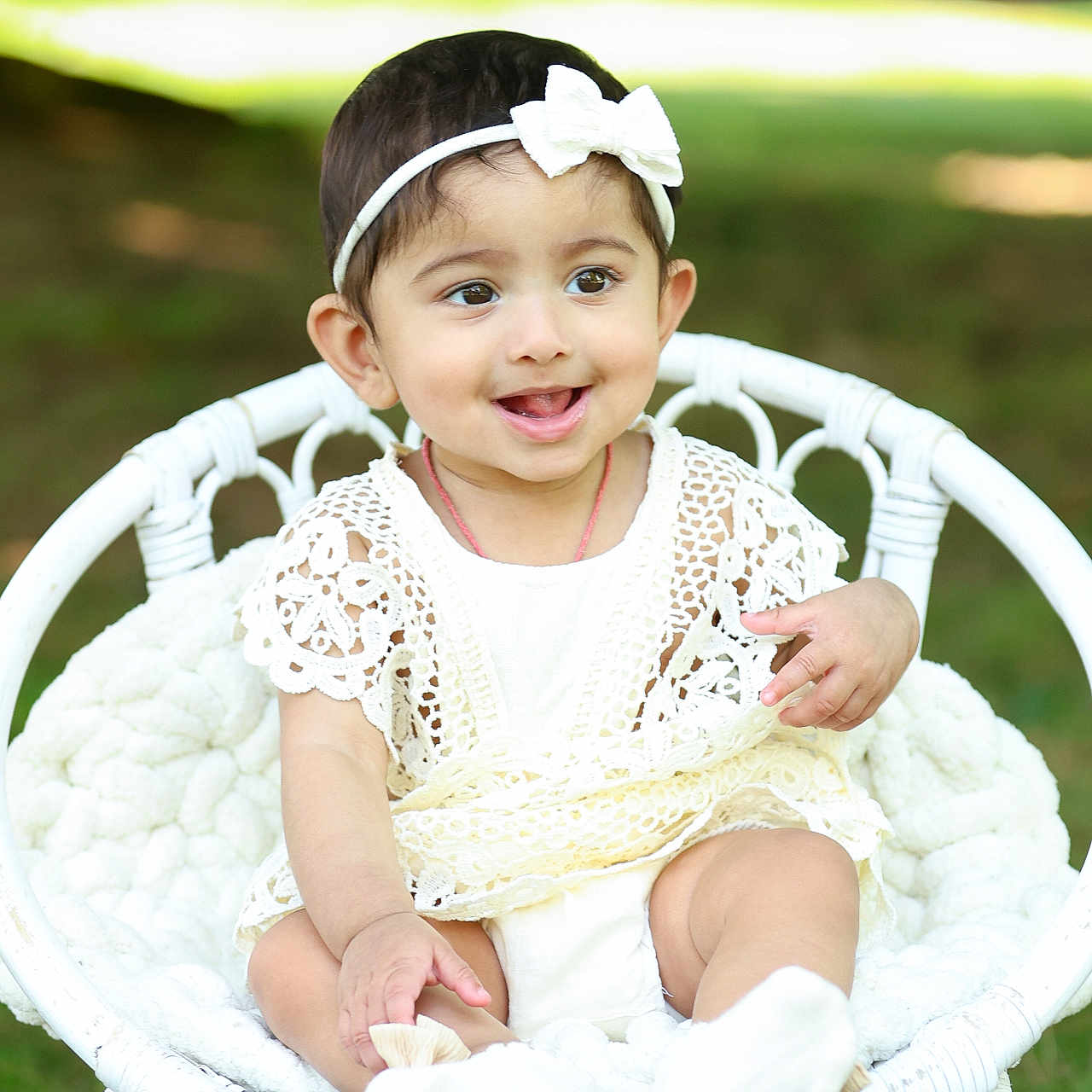 Thryambika is registered to the contest to win money with this photo: baby, child, cute, grass, greenery, happy, headband, infant, lace_dress, nature, outdoor, playful, portrait, sitting, smiling, soft_blanket, sunlight, white_bow, white_clothing, wicker_chair