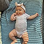 baby, infant, headband, bow, onesie, textile, blanket, knitted, blue, pink, tongue_out, playful, cute, chubby, skin, couch, light_and_shadow, indoor, smiling, person