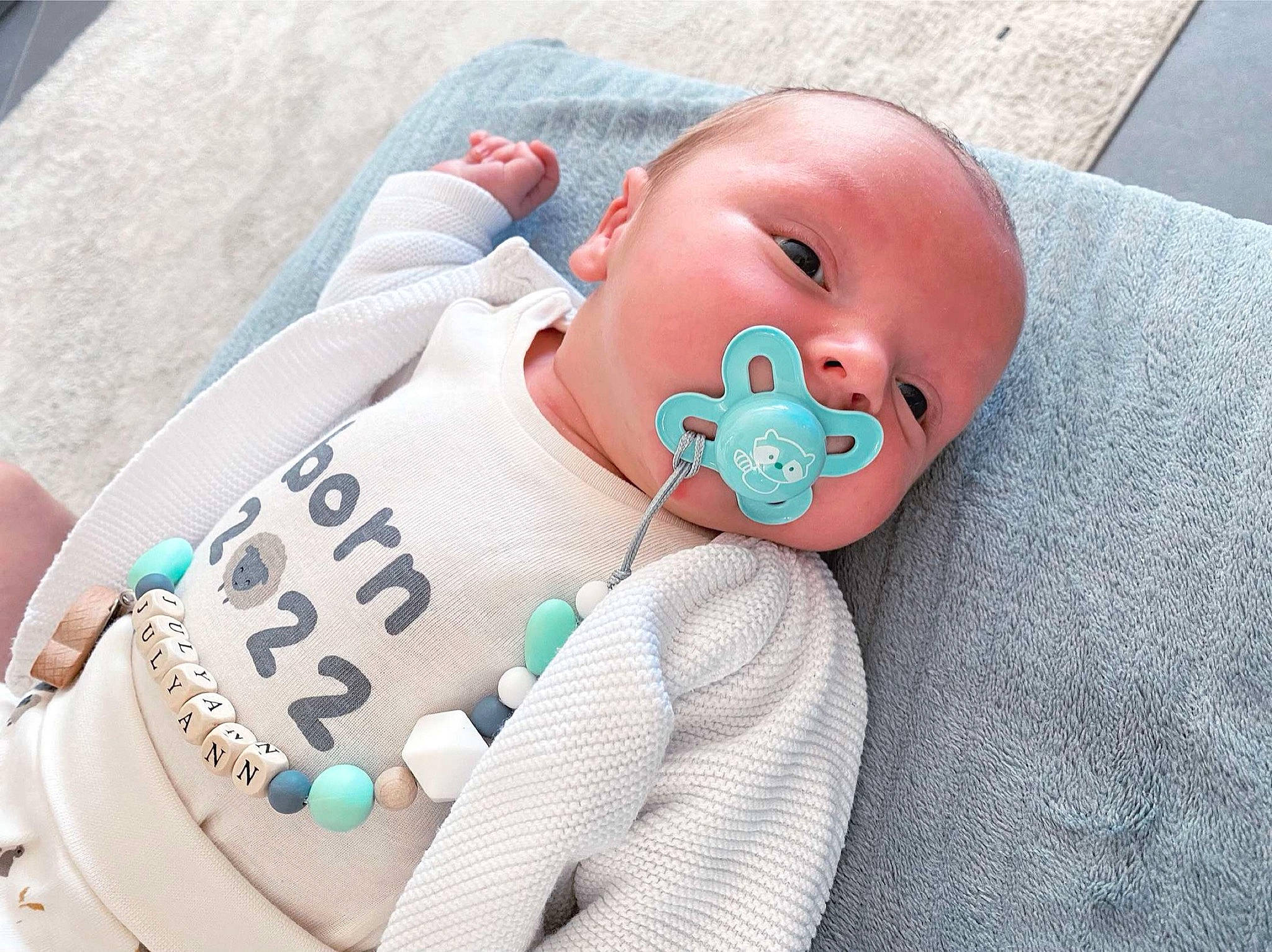 Julyann a rejoint le concours — aidez-le/la à gagner de superbes lots ! baby, baby_products, baby_safety, baby_sleeping, baby_toddler_clothing, carmine, cheek, child, comfort, finger, flesh, happy, linens, pattern, person, sitting, sleeve, toddler