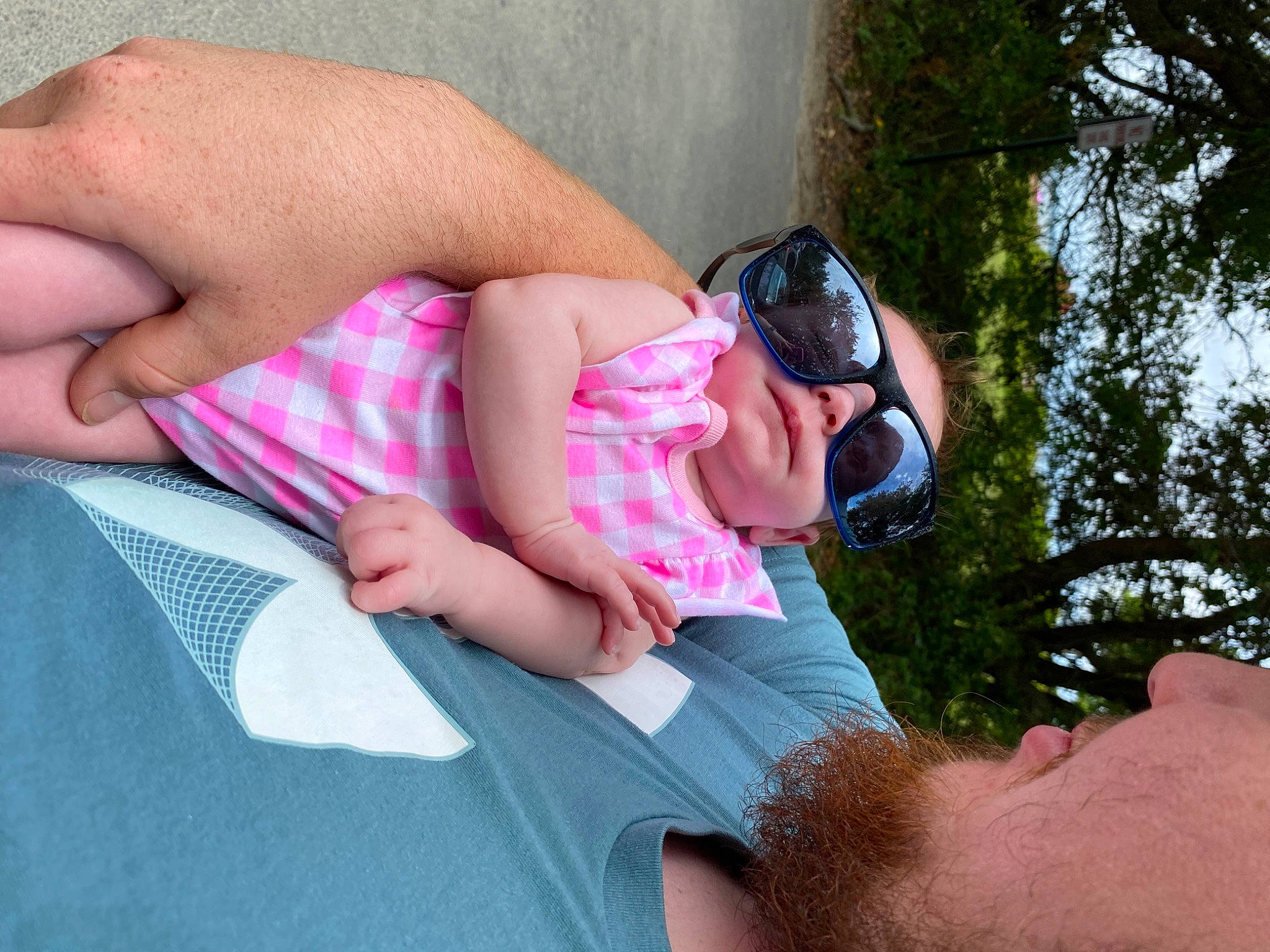 Kinsley is registered to the contest to win money with this photo: arm, comfort, eyewear, finger, gesture, glasses, goggles, grass, hand, human_body, leg, leisure, mammal, muscle, person, pink, skin, sunglasses, thigh, toddler