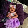 Nevaeh is registered to the contest to win money with this photo: baby, infant, smiling, purple_skirt, headband, bow, bed, blanket, clothing, cute, happy, person, skin, foot, hand, indoor, portrait, tutu, child, sleeping_area