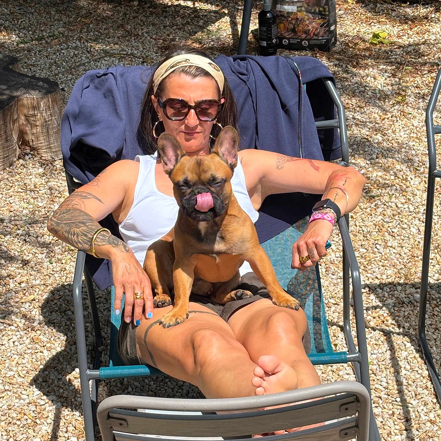 Vince a rejoint le concours — aidez-le/la à gagner de superbes lots ! woman, dog, french_bulldog, outdoor, sunglasses, chair, tattoo, sunlight, relaxing, summer, pet, tongue_out, casual, headband, barefoot, gravel, arm_chair, jewelry, shorts, tank_top