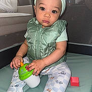 Jayce joined the competition — help win amazing prizes! baby, child, infant, playpen, toy, cup, green_vest, hat, sitting, pajamas, red_block, floor_mat, indoors, cute, curious, small_child, face, hands, legs, expression