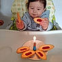 toddler, child, high_chair, cookie, candle, plate, food, indoors, baby, table, snack, celebration, happy, curious, person, sitting, clothing, face, hand, light