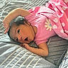 baby, infant, child, portrait, bed, bedding, blanket, pink_clothing, striped_sheets, hearts, lying_down, wide_eyes, dark_hair, smiling, indoors, bedroom, cozy, cuddly, relaxed, photography