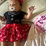 baby, infant, pacifier, red_bow, minnie_mouse, dress, polka_dots, bed, blanket, pillow, milestone_card, 2_months, cute, child, person, headband, socks, lying_down, soft_lighting, indoors