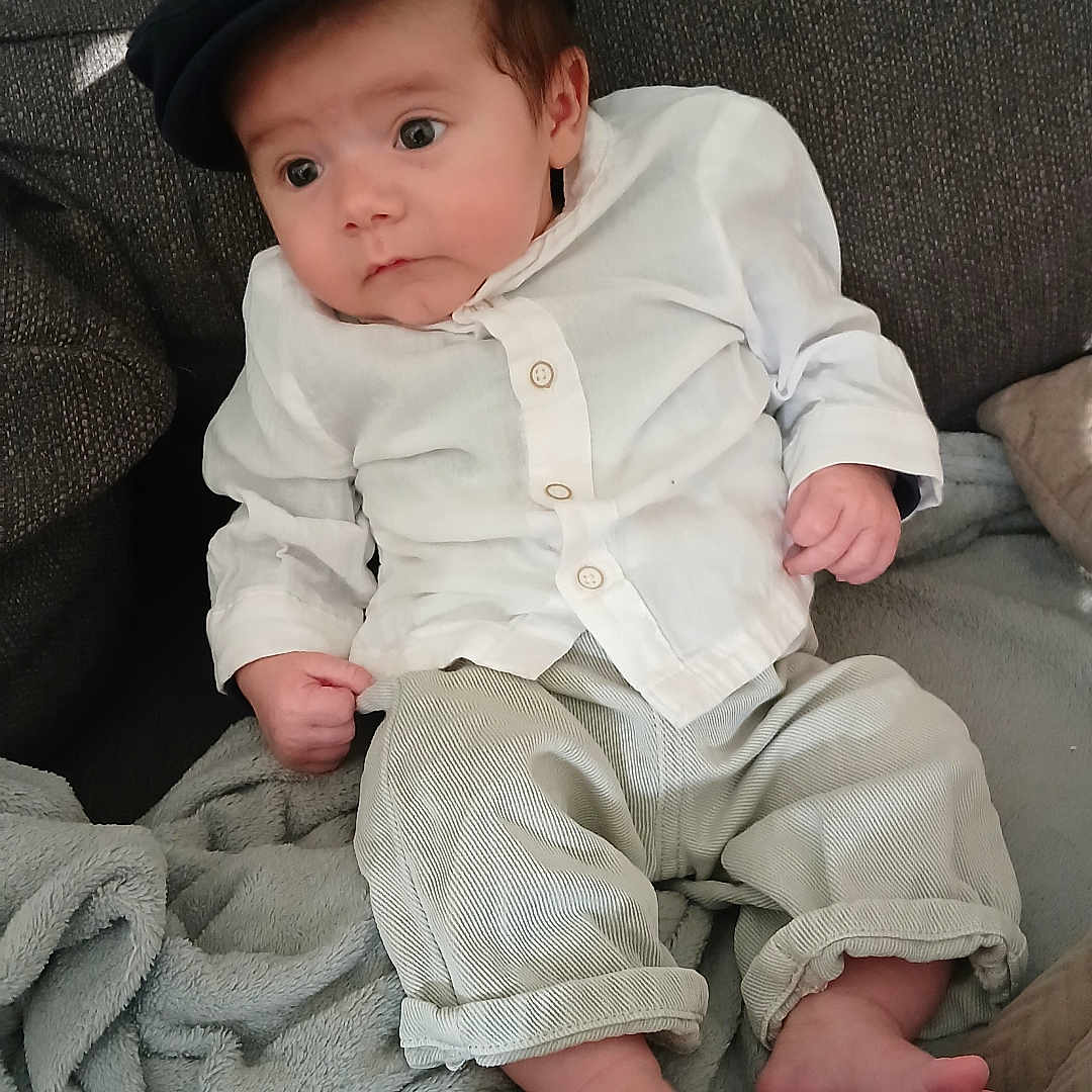 Lyam participe au concours pour gagner de l'argent avec cette photo : baby, bodypart, cap, clothing, couch, cushion, face, finger, furniture, hand, hat, head, homedecor, linen, pants, person, photography, portrait, shirt, sitting